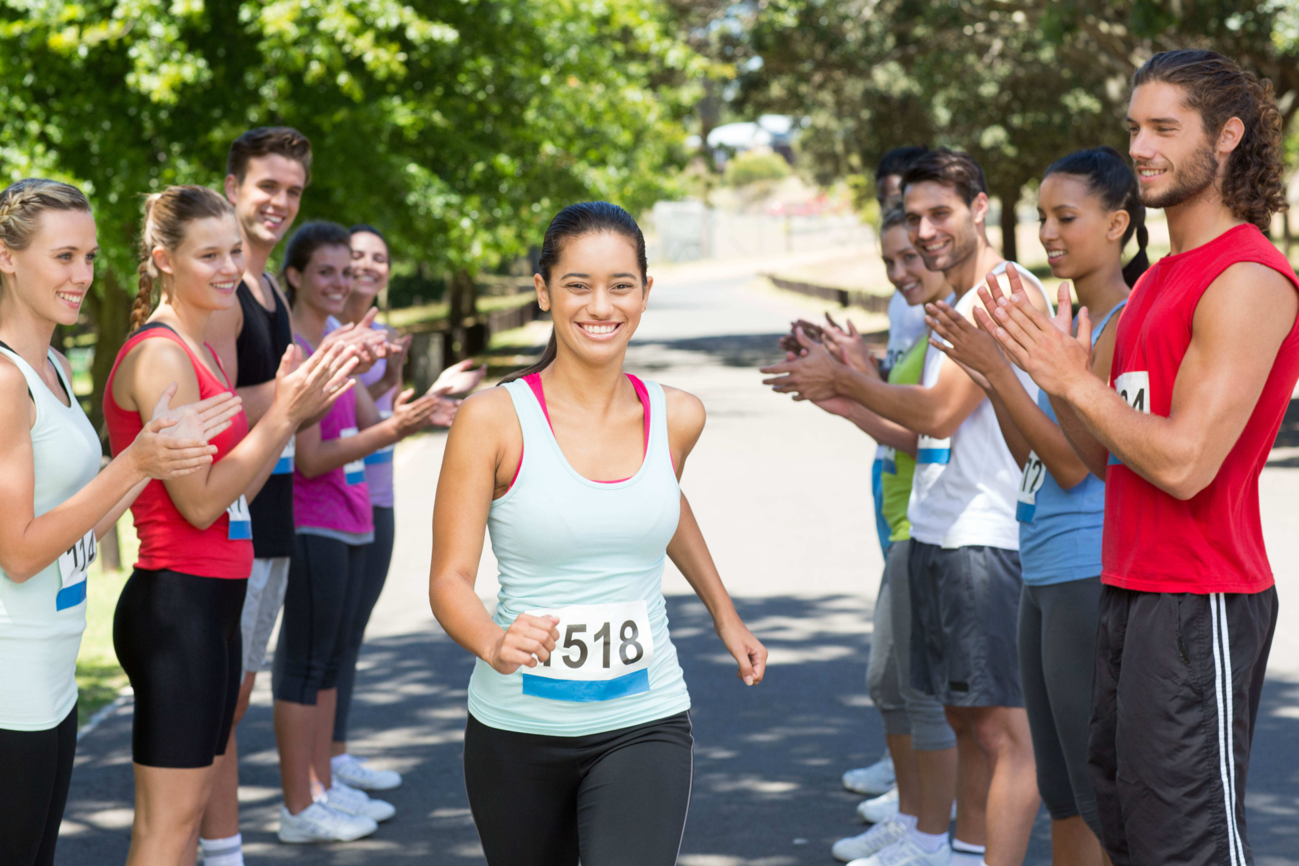 A girl crossing the finish line of a marathon with people clapping on either side of her