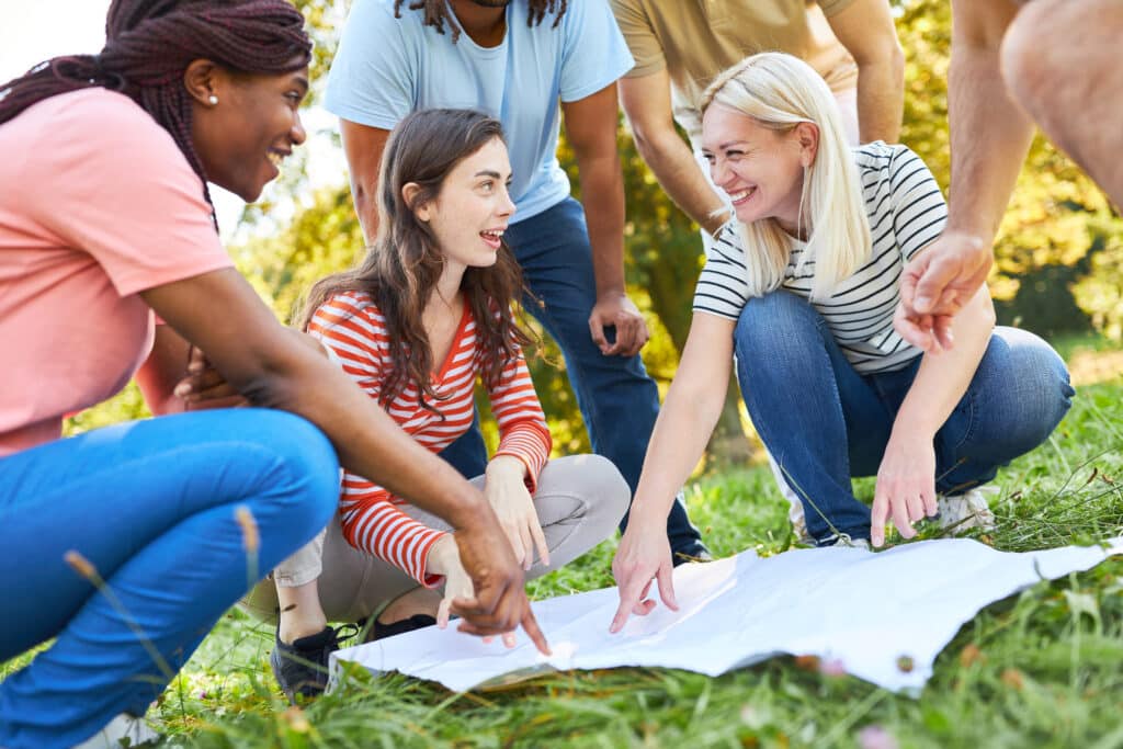 Group of young people doing geocaching as a scavenger hunt for teamwork and cooperation